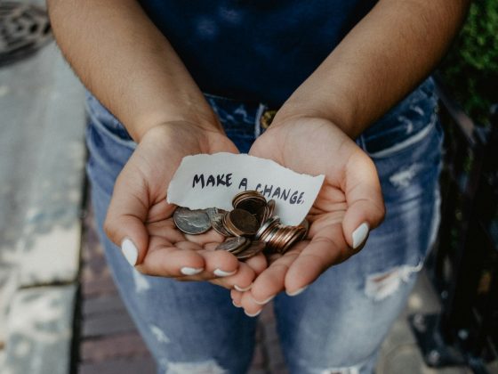 person showing both hands with make a change note and coins