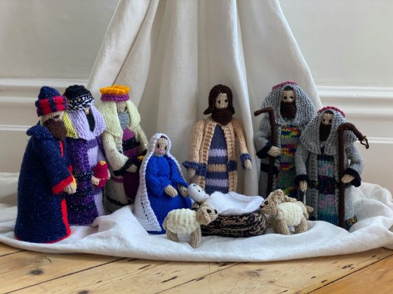 three white and blue knitted dolls on white textile