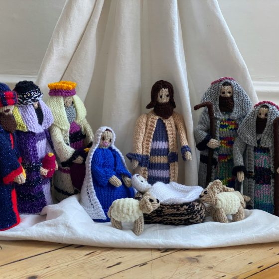 three white and blue knitted dolls on white textile